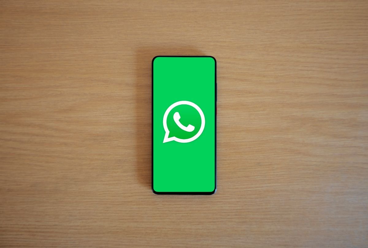 Smartphone displaying the WhatsApp logo on a wooden table