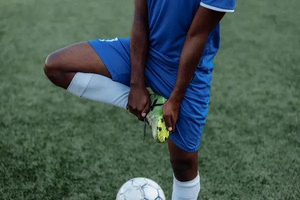 Footballer pulling on a boot and sock before a match