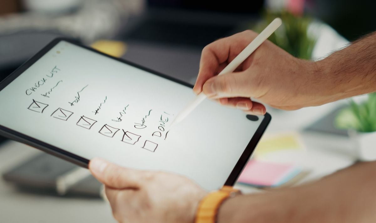 Hand marking items on a digital checklist on a tablet with a stylus pen