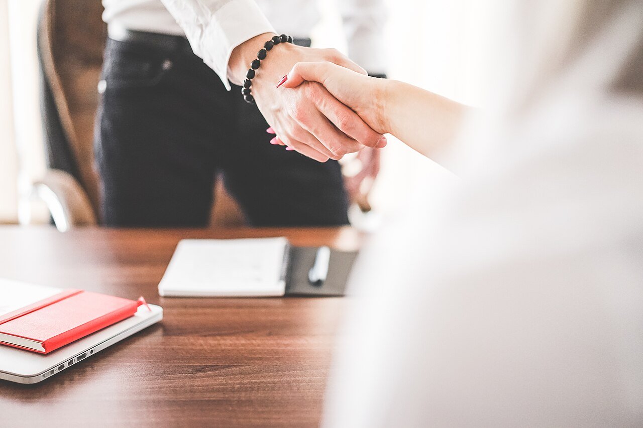 Two professionals shaking hands in an office after agreeing on salary