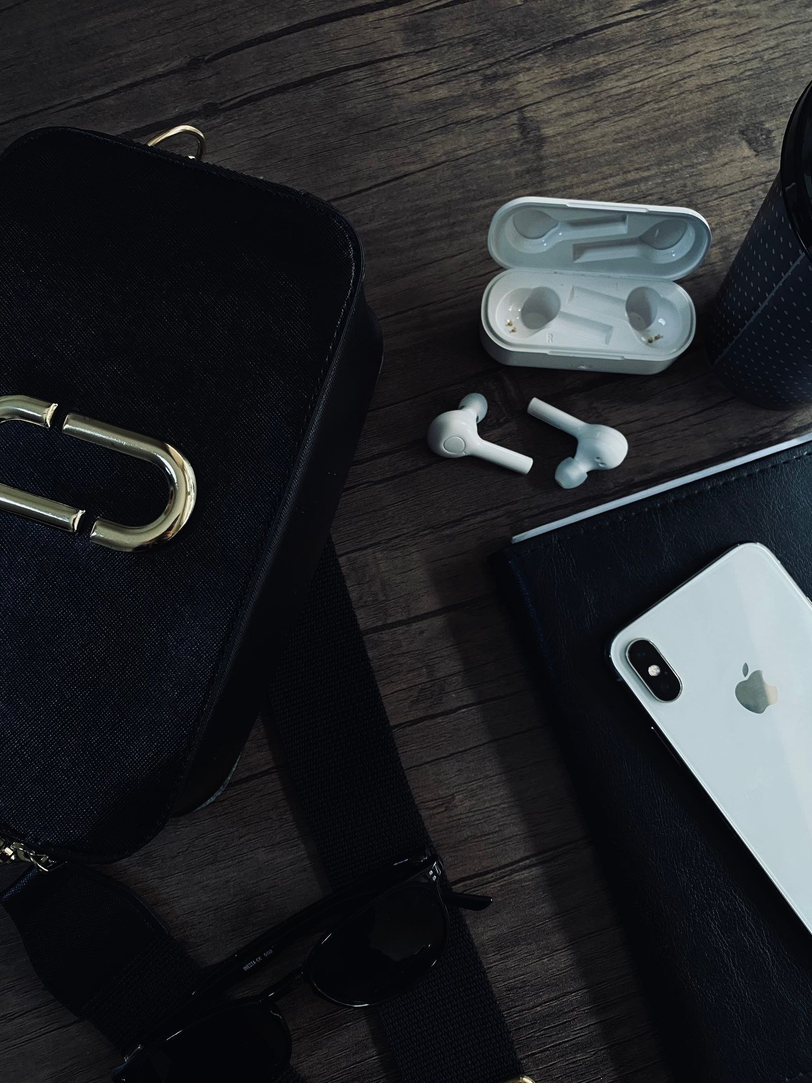 Wireless earbuds with charging case and smartphone on a wooden desk