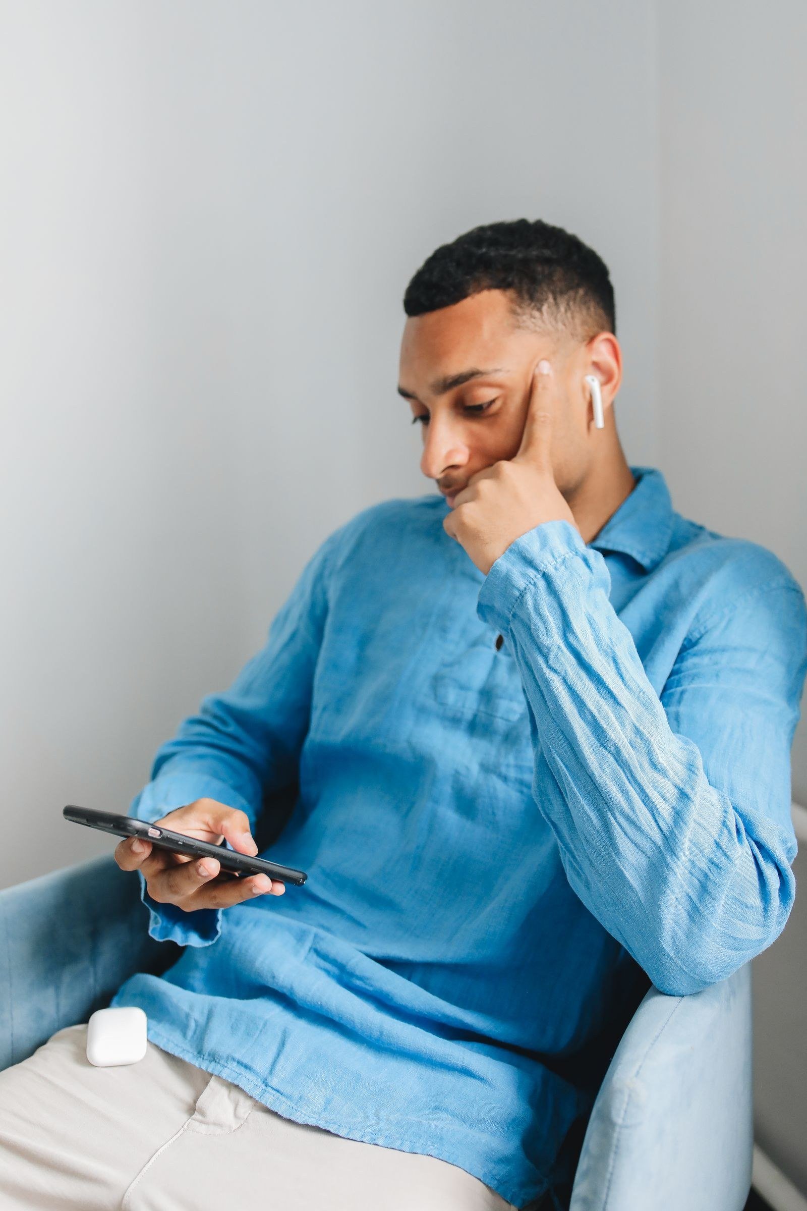 Man wearing a wireless earbud while using a smartphone
