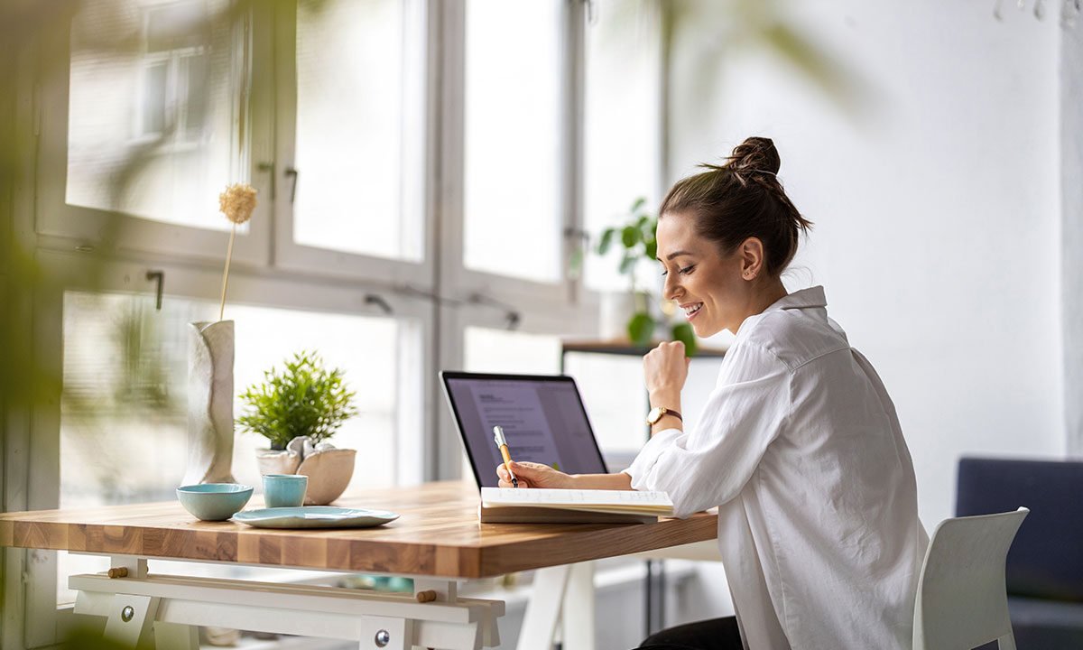 Small business owner writing emails on a laptop at her desk