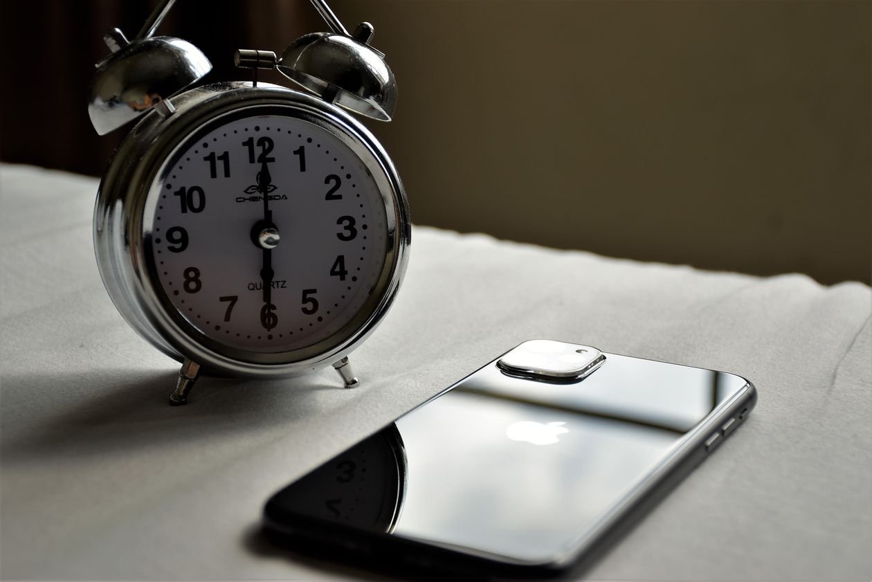 Classic twin bell alarm clock beside an iPhone used as a backup alarm