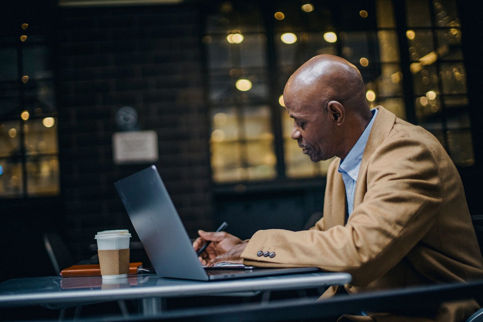 Business owner working on a laptop in a cafe while setting up his newsletter