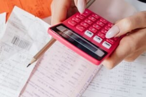 Small business owner using a calculator to review invoices and receipts before a customer credit check