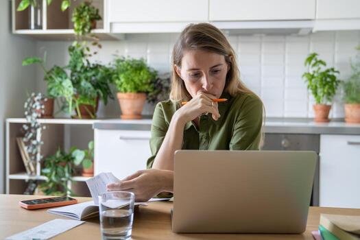 Freelancer reviewing an overdue invoice on a laptop at her home office desk