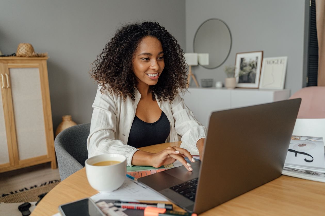 Freelancer smiling while working on a laptop at a home office desk