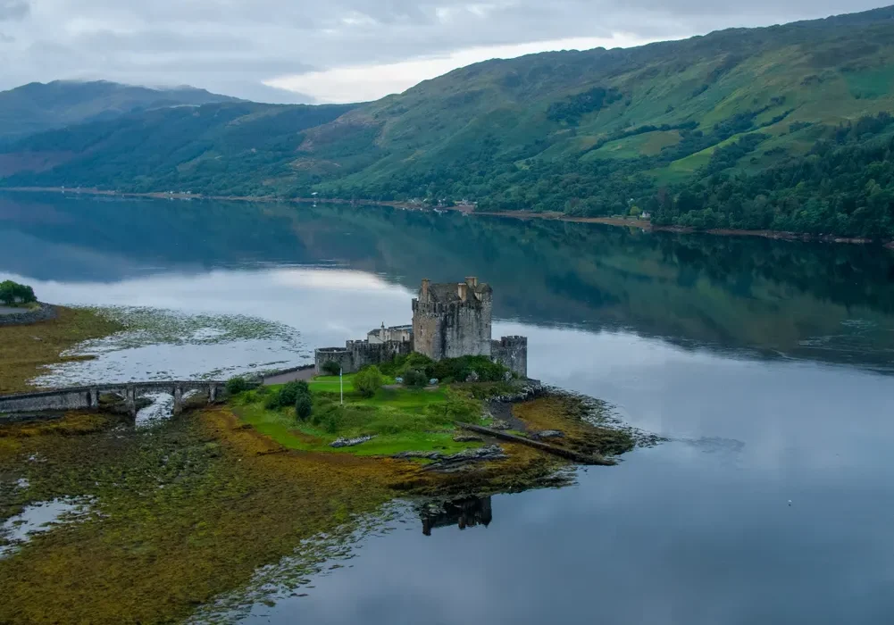 Eilean Donan Castle on a calm loch surrounded by green hills in the Scottish Highlands