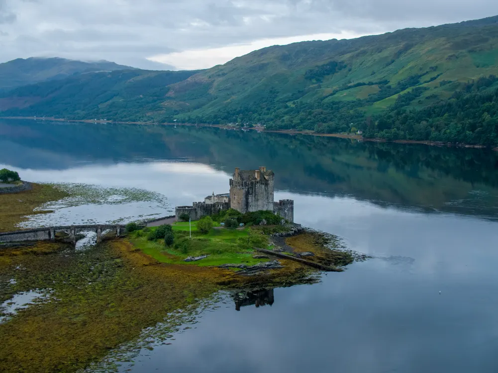 Eilean Donan Castle on a calm loch surrounded by green hills in the Scottish Highlands