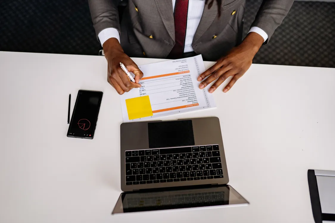 Small business owner reviewing a printed contingency plan at a desk with a laptop