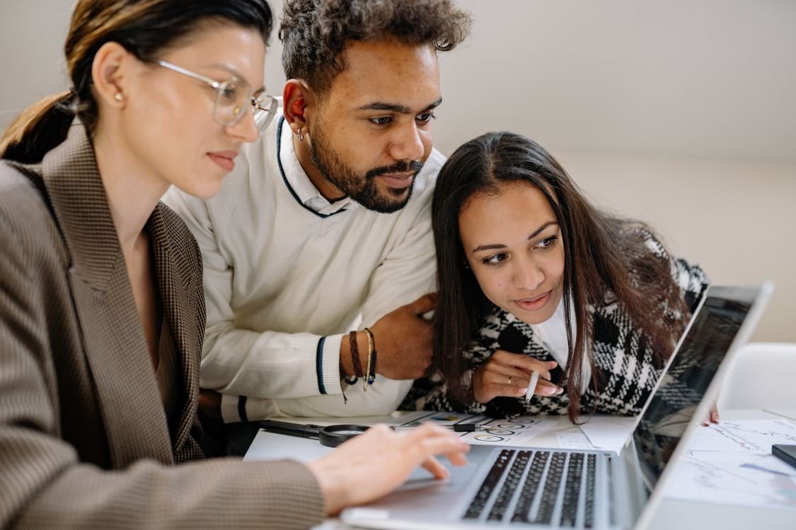 Three colleagues reviewing company logins on a laptop during a security audit