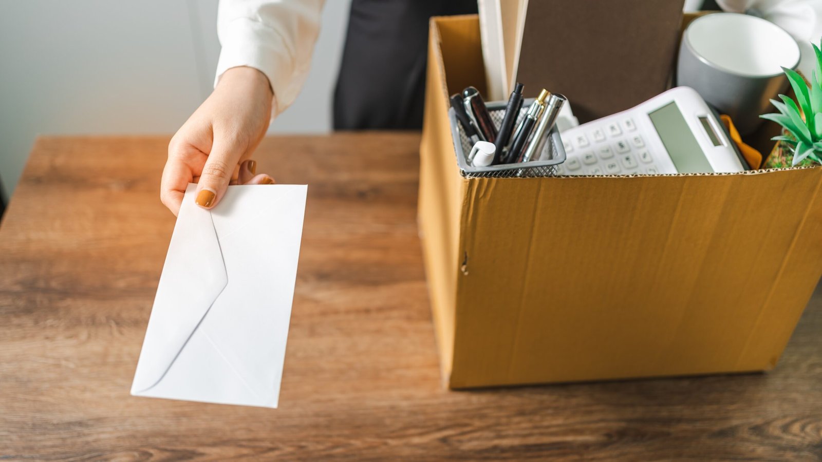 Business woman holding a resignation letter while packing her desk