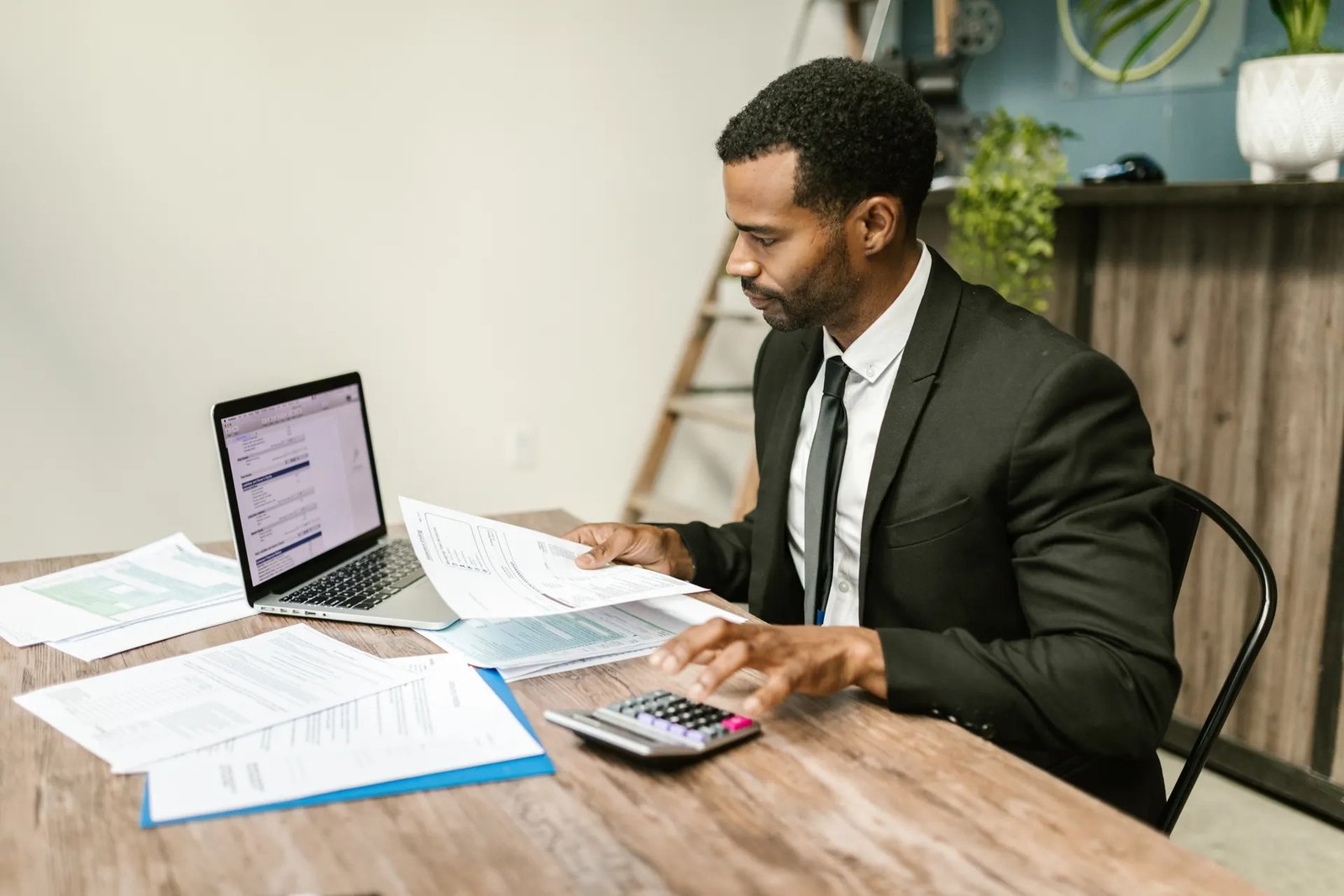 Businessman reviewing invoice paperwork and using a calculator at his desk