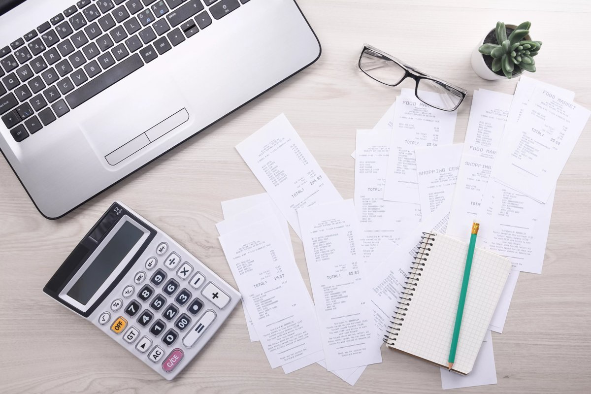 Calculator next to a stack of unpaid bills and invoices on a desk