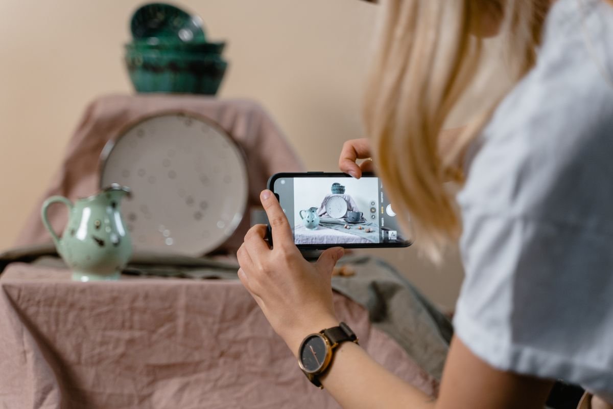 Small business owner photographing handmade pottery with a smartphone for social media content