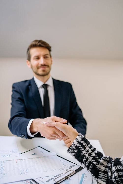 Two colleagues shaking hands in an office as one departs on good terms