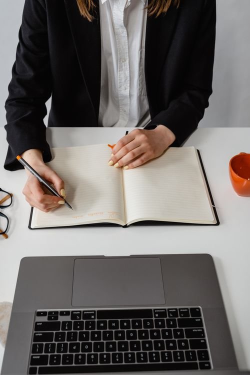 Business owner writing notes in a planner while reviewing a client relationship