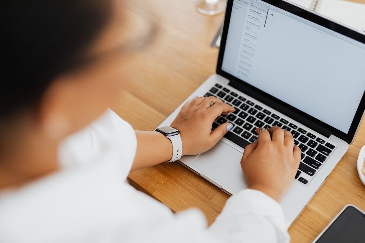 Woman typing a business email in English on a laptop with the inbox open on screen