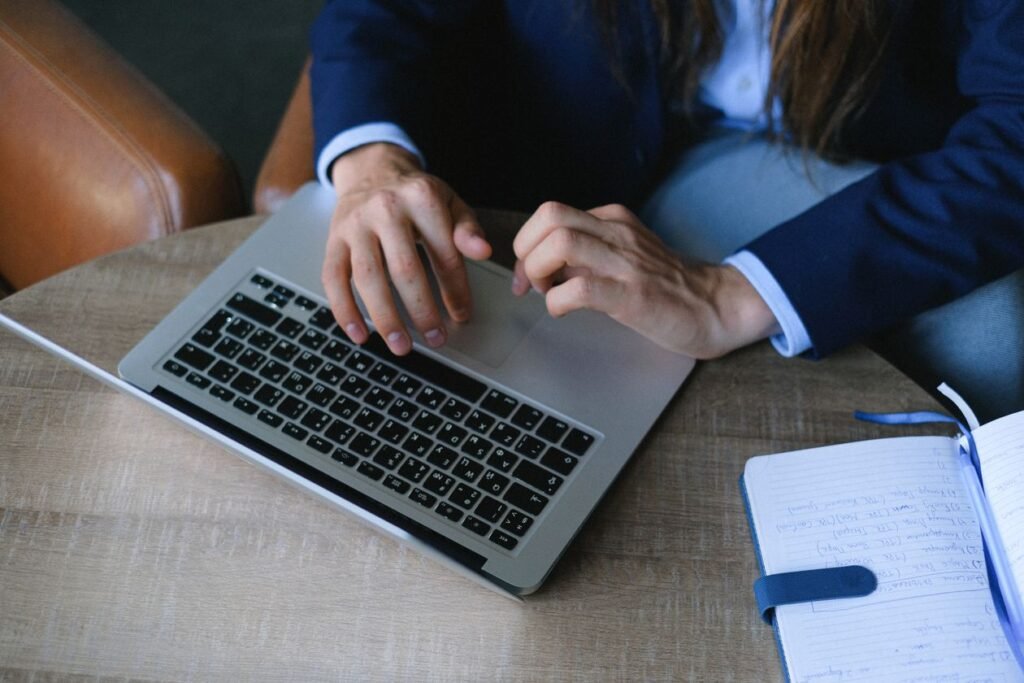 Entrepreneur writing notes in a notebook during a customer interview at a wooden desk