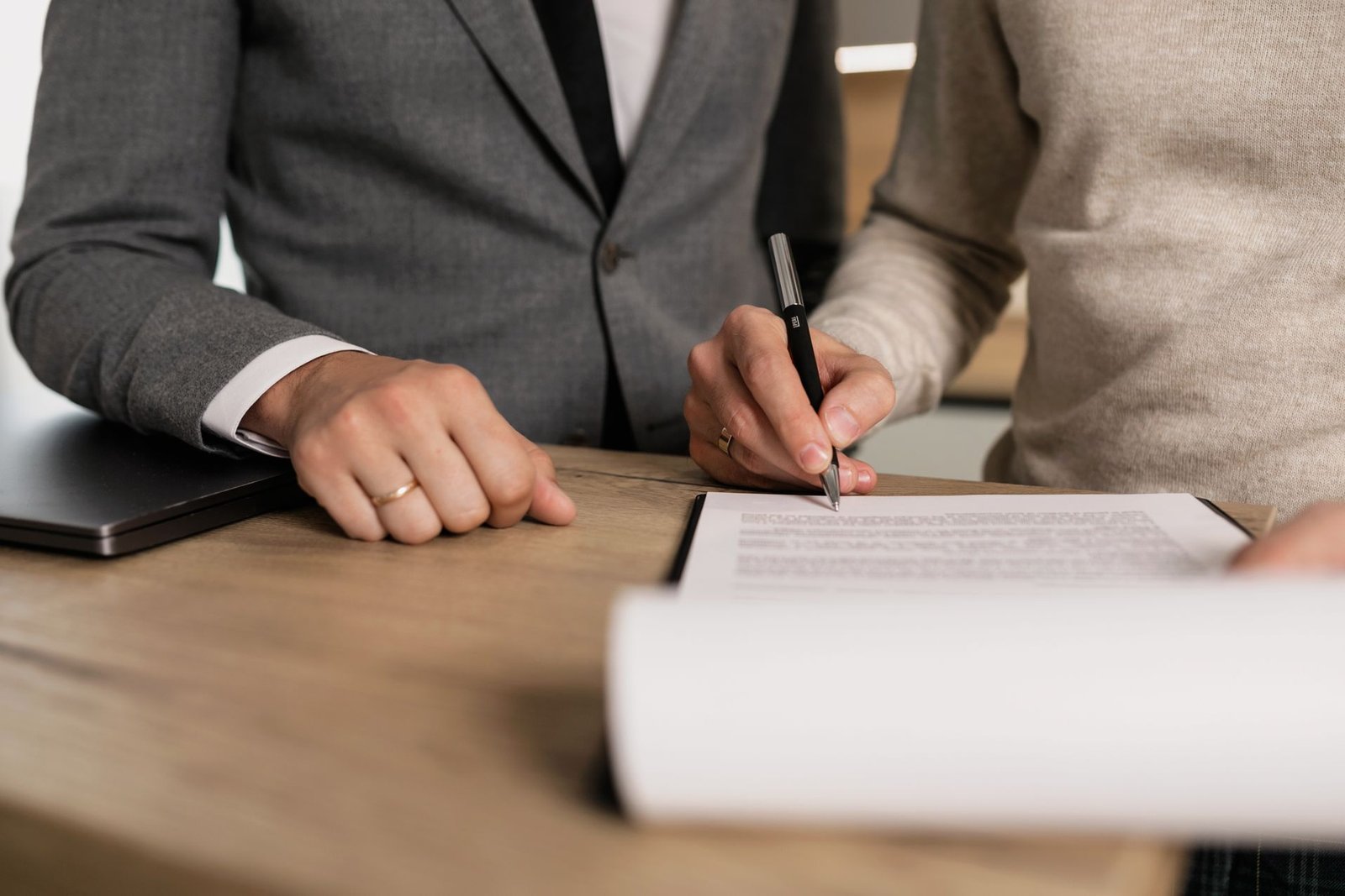 Business person signing a client contract with a pen at a desk