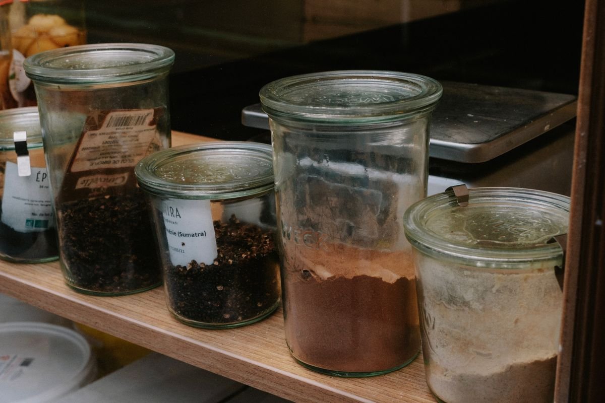 Spices stored in clean glass jars lined up on a kitchen shelf