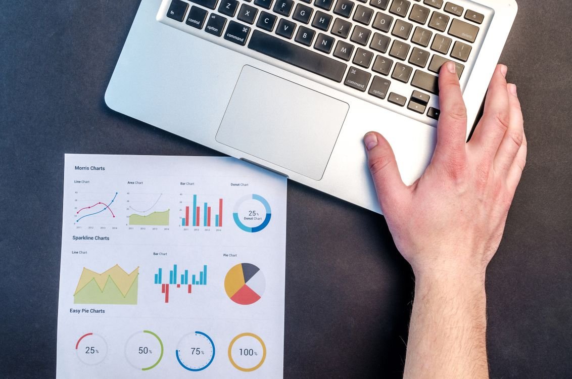 Laptop next to a printed page of financial charts used to review a customer credit position