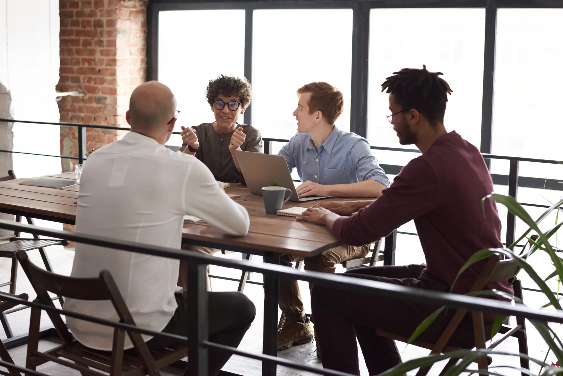 Small business team discussing risk plans around a table with a laptop