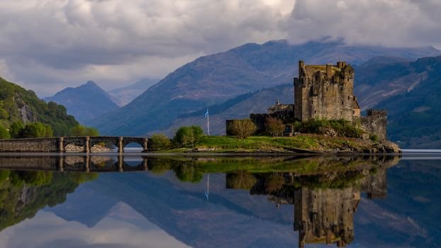 Eilean Donan Castle reflected in a still loch beneath mountains in the Scottish Highlands