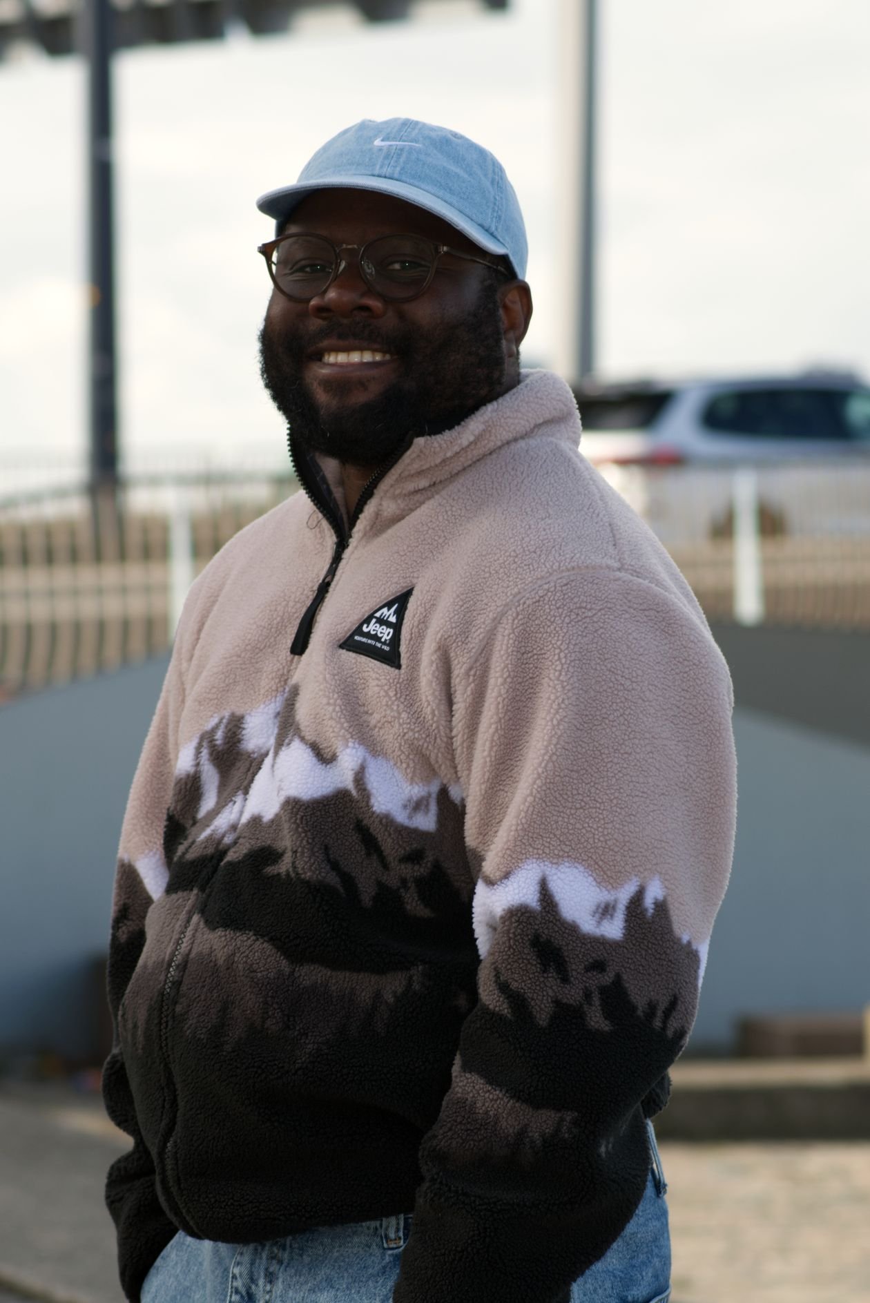 Smiling man wearing a baseball cap outdoors on a sunny day