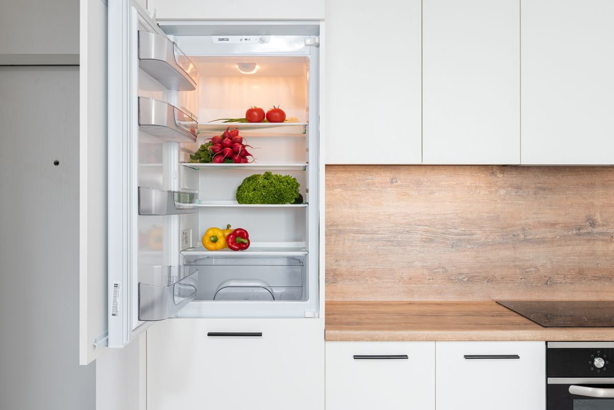 Open refrigerator with a small selection of fresh vegetables on the shelves