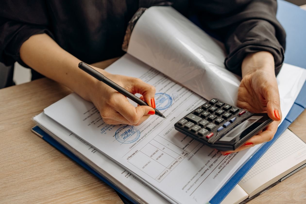 Freelancer reviewing invoice paperwork with a calculator