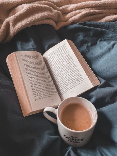 Open book next to a cup of coffee on a table