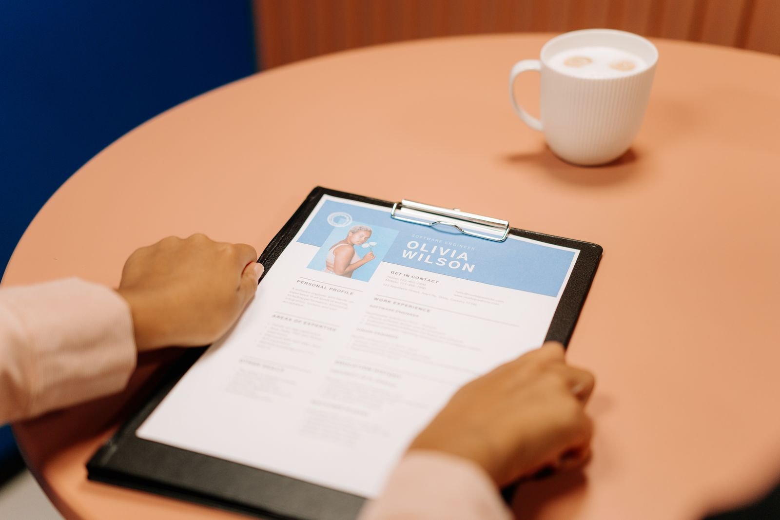 Recruiter reviewing a job application CV on a clipboard beside a coffee cup