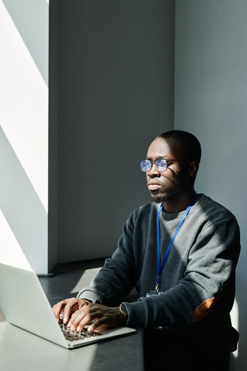 Man working on a laptop near an office window