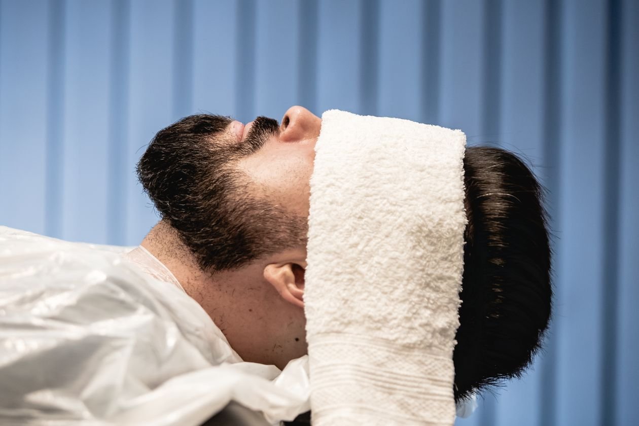Man relaxing with a warm towel over his eyes