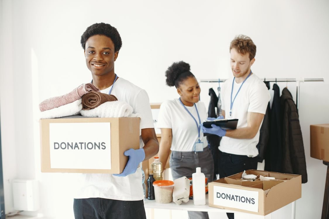 Charity volunteers sorting a cardboard box labelled donations during a spare room clear out