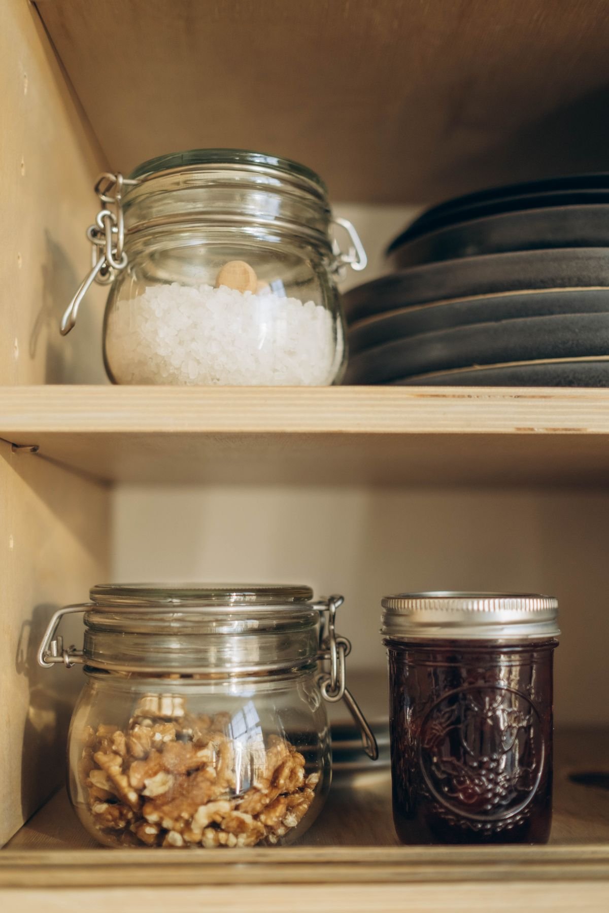 Glass containers with walnuts salt and preserves on pantry shelves