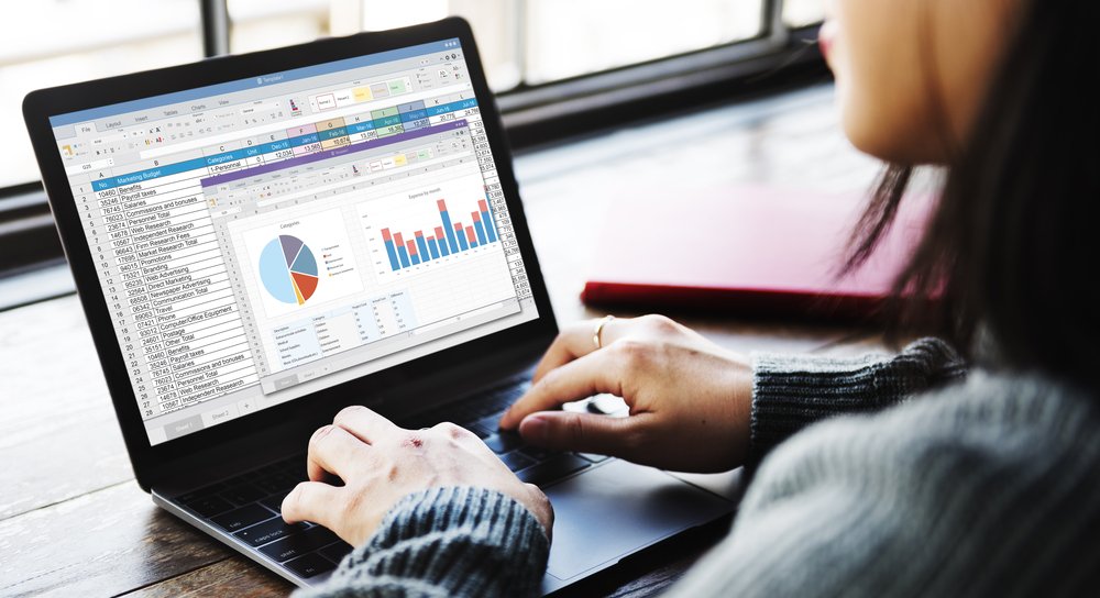 Laptop showing a business spreadsheet with pie and bar charts for planning analysis