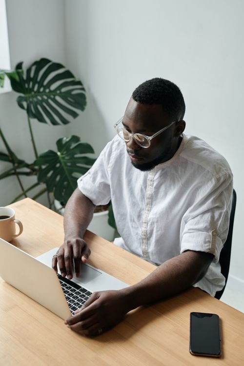 Man typing on a laptop at a bright home office desk