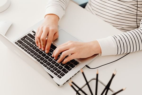 Close up of hands typing a follow up email on a laptop keyboard