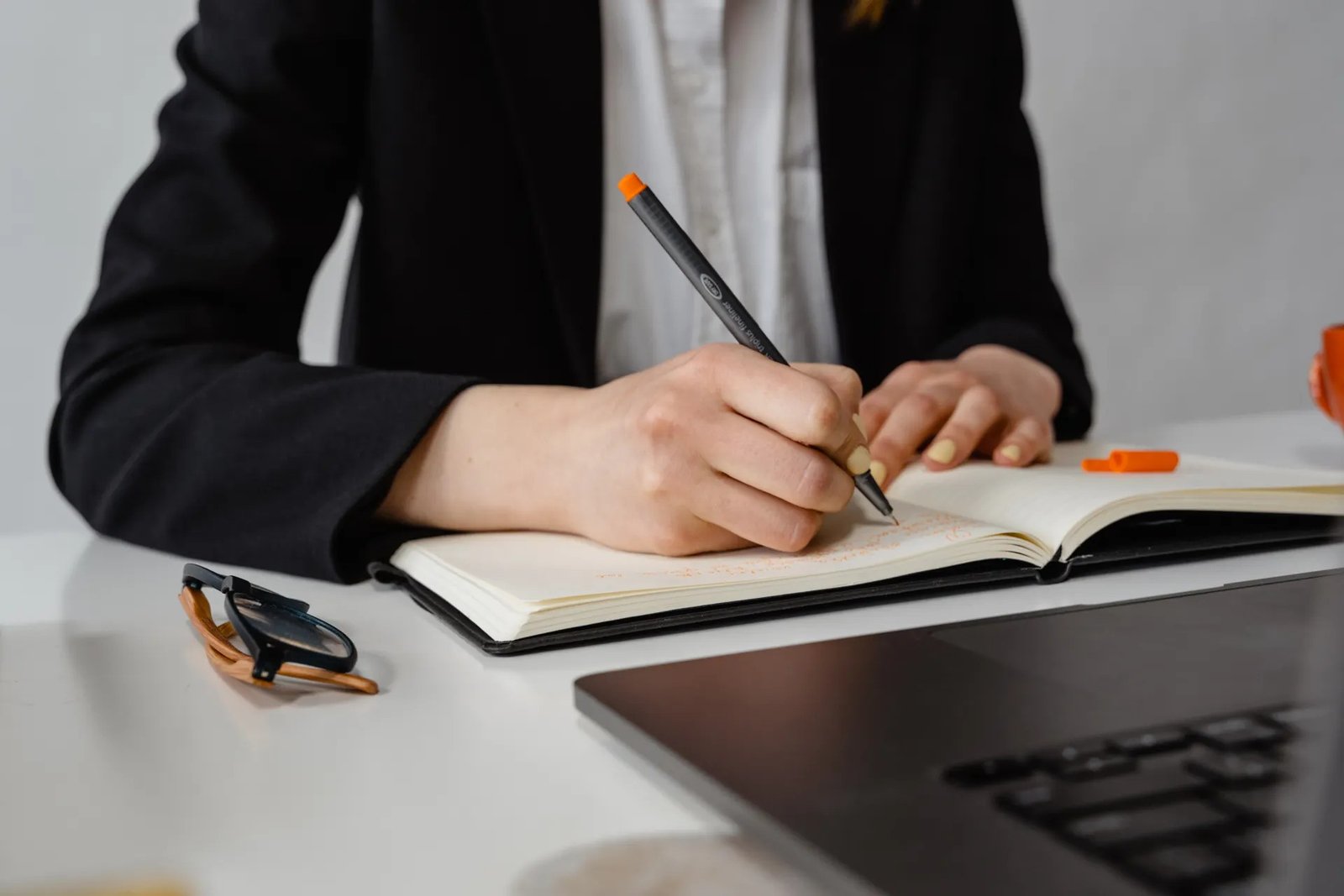 Person writing work notes in a notebook at a desk