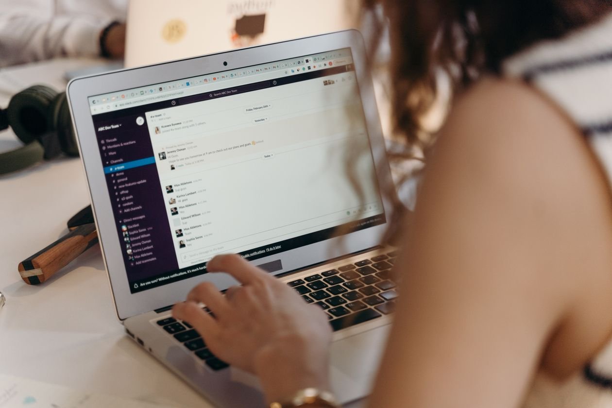 Businesswoman working on a laptop with team messages visible on the screen