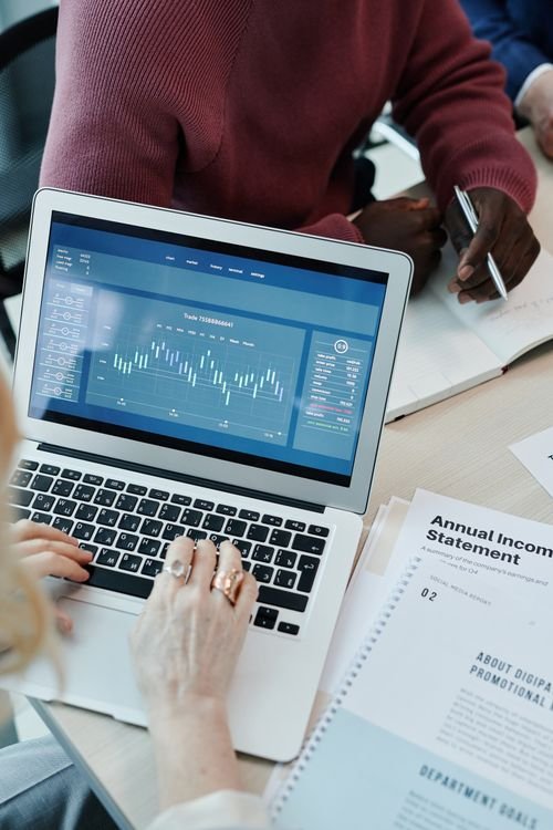 Laptop beside an annual income statement while reviewing business credit information