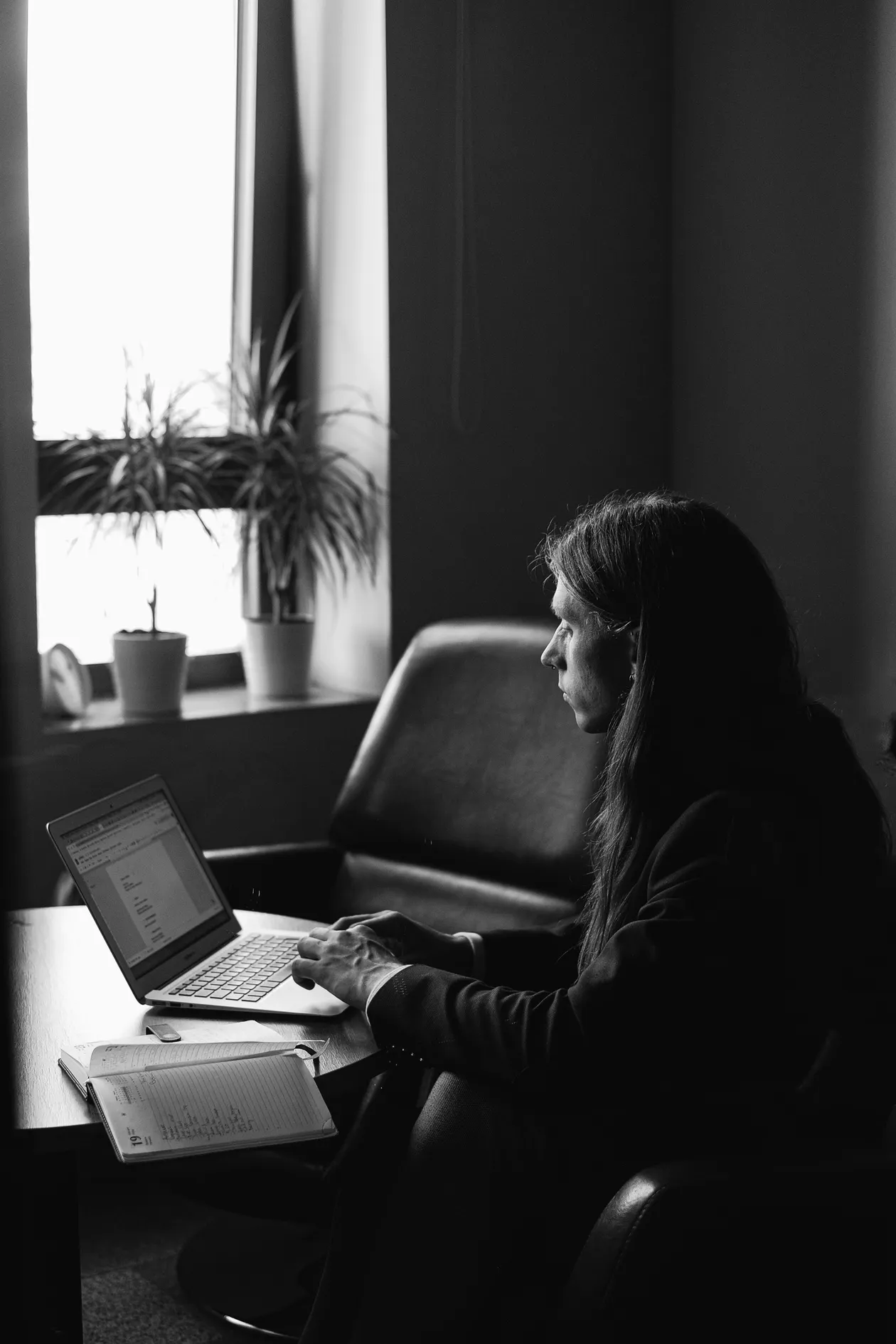 Entrepreneur typing on a laptop with a notebook beside them