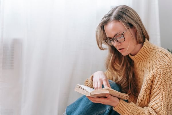 Woman reading a book by a bright window