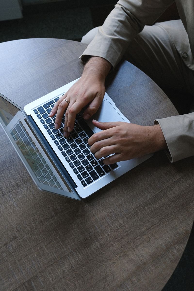 Person typing on a laptop at a round office table