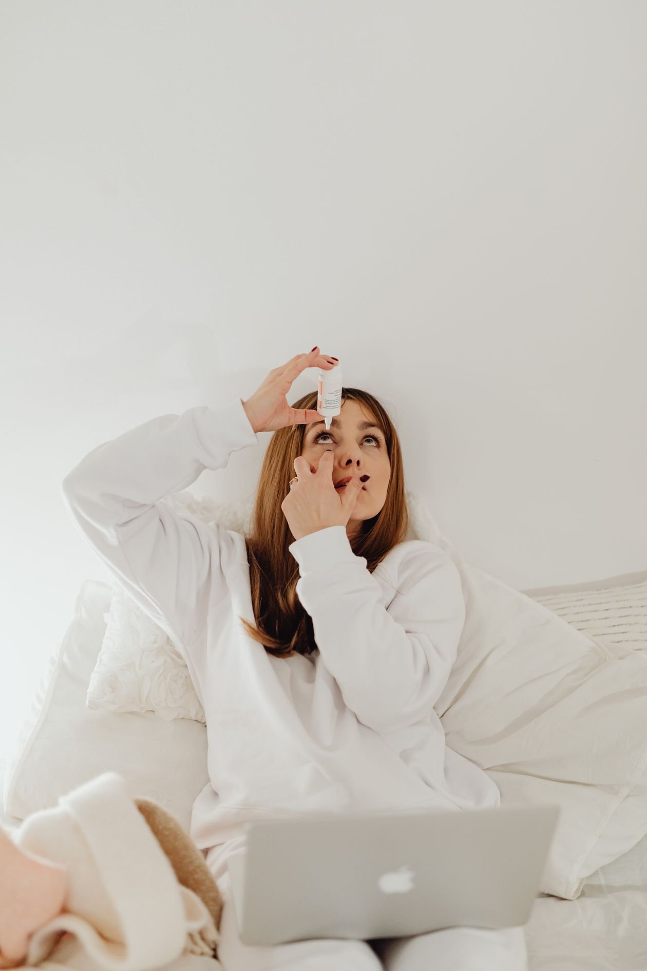 Woman applying lubricating eye drops at home