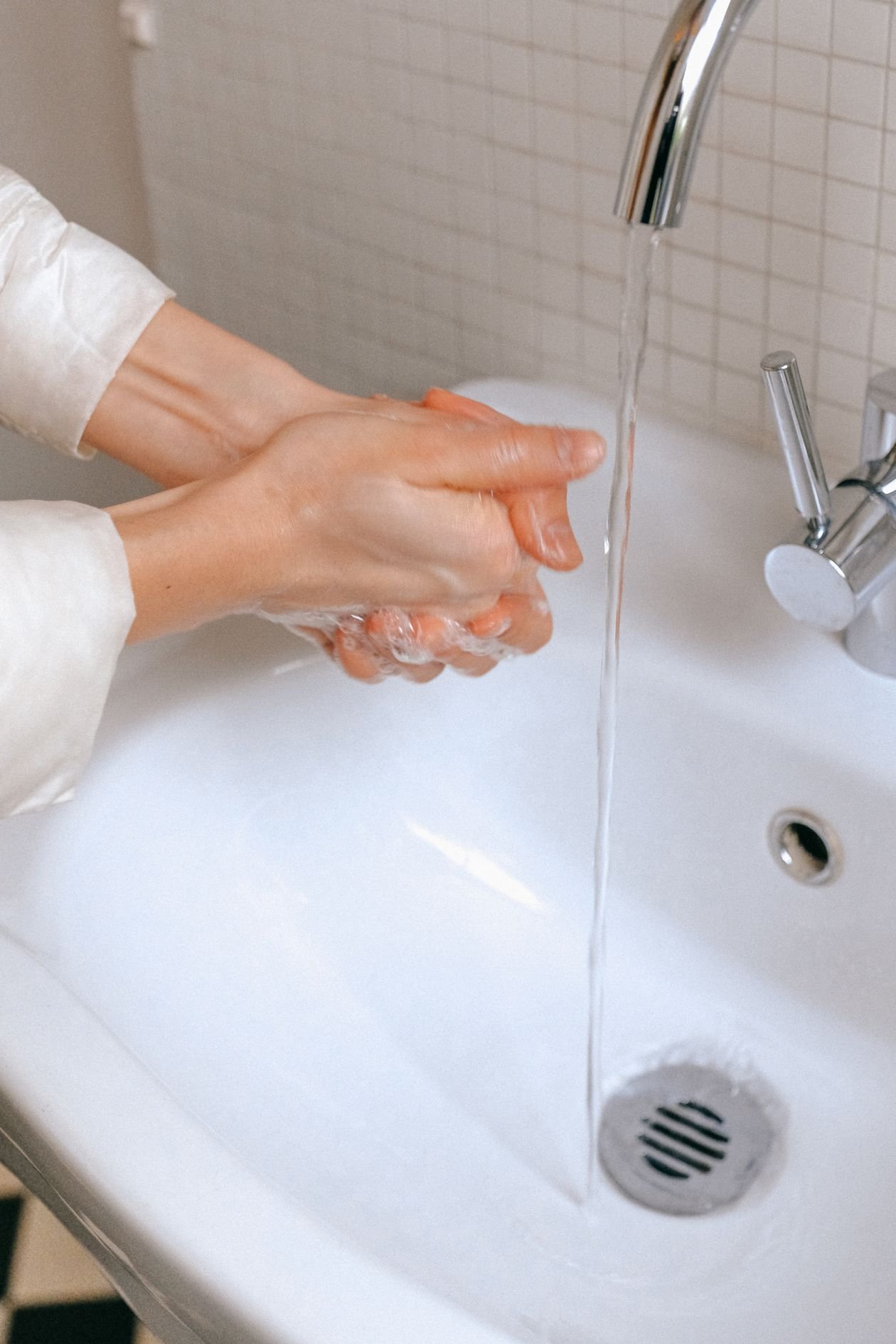 Hands rinsing under cool running water from a faucet