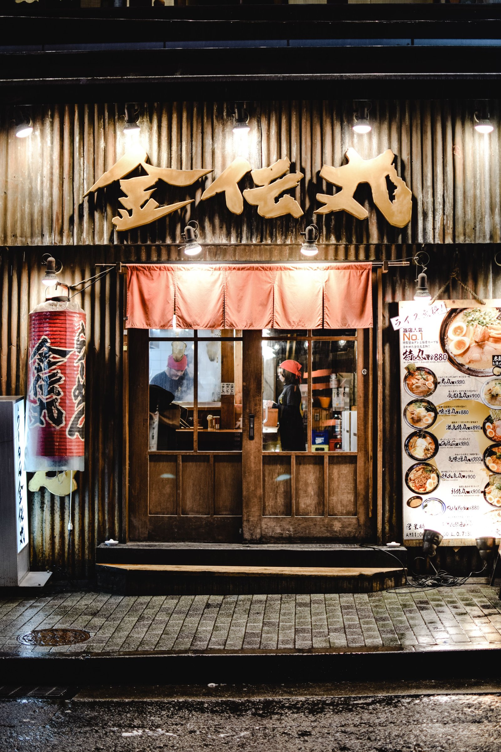 Ramen shop storefront in Japan at night with menu prices in yen